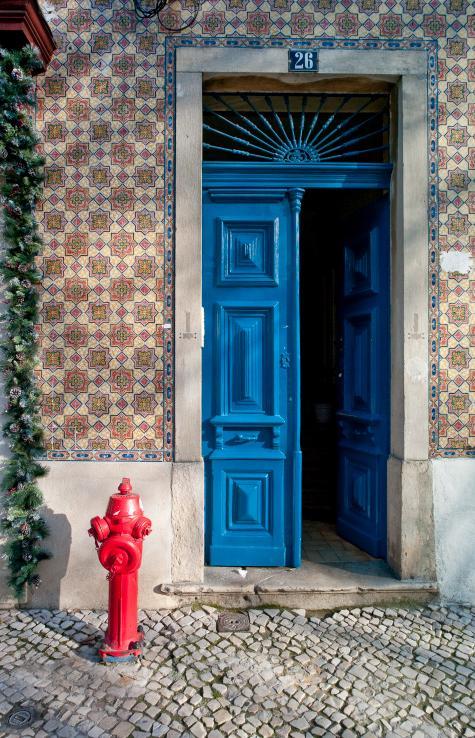 Blue painted front door and tiled building exterior with fire hydrant, Lisbon, Campo de Ourique