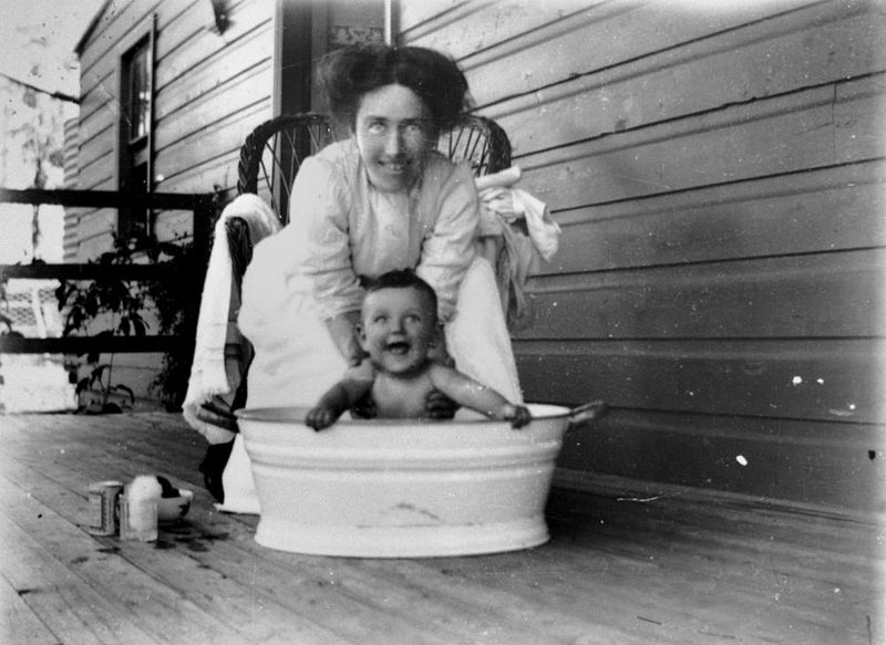 800px-statelibqld_1_128206_woman_bathing_a_child_on_a_verandah_1900-1910