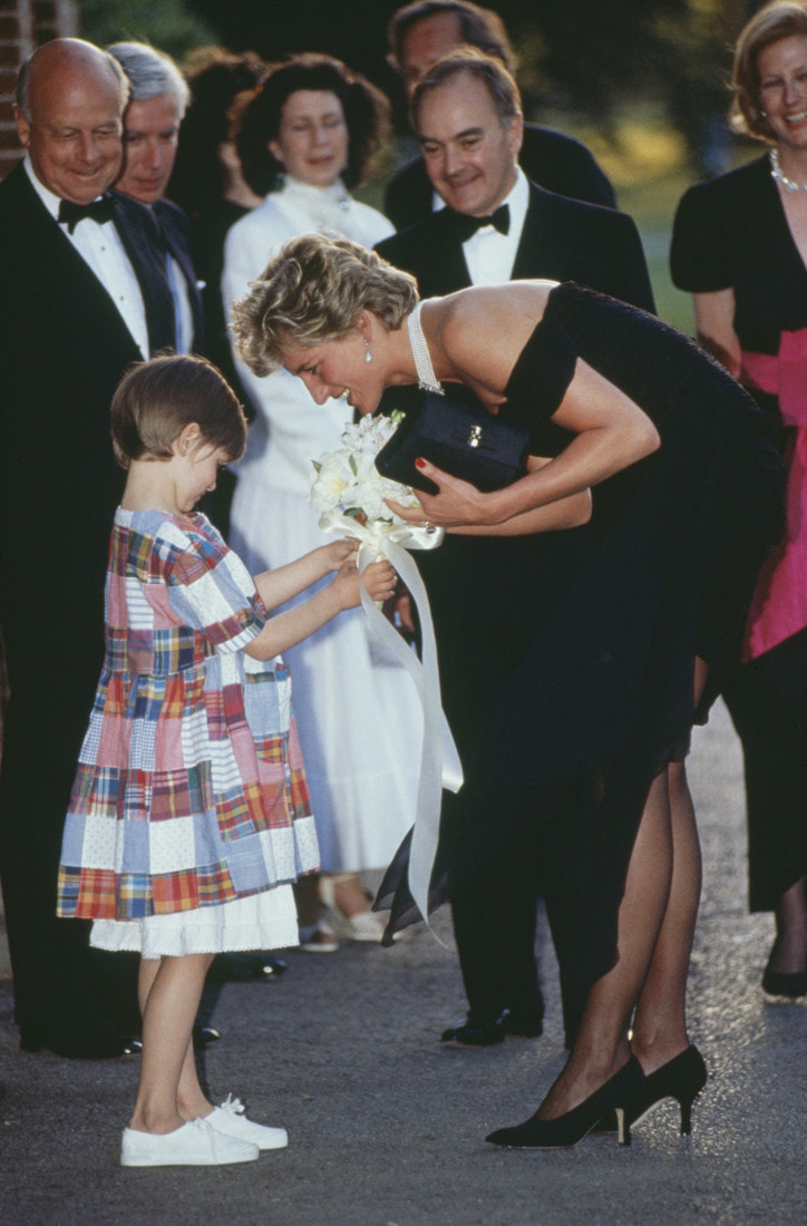 Princess Diana (1961 - 1997) receives a bouquet from a young girl, as she arrives for a gala event at the Serpentine Gallery, London, 29th June 1994. The princess is wearing a black gown by Christina Stambolian. (Photo by Tim Graham/Getty Images)