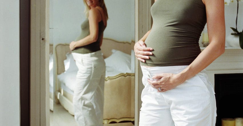Pregnant woman looking at reflection in mirror